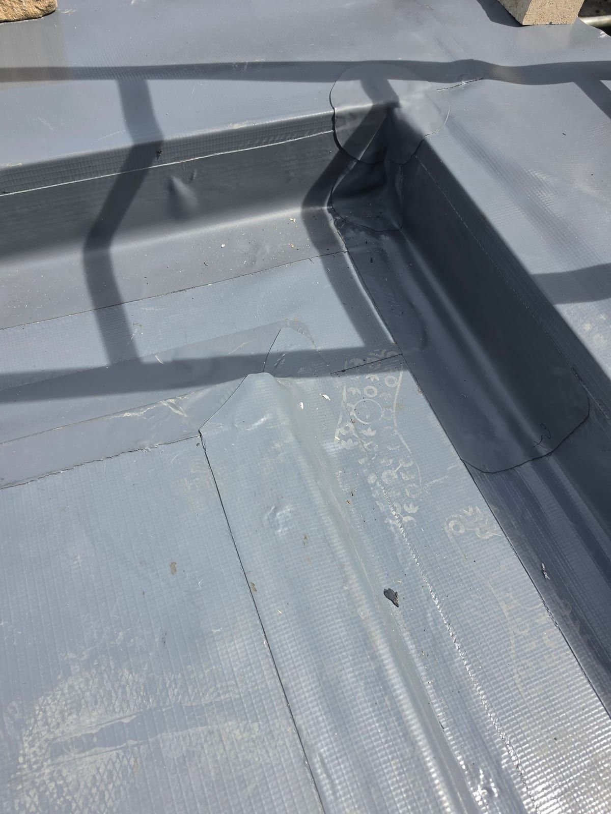 Close-up of hot-air welded laps and a reinforced internal corner on a dark grey Fatra PVC roof