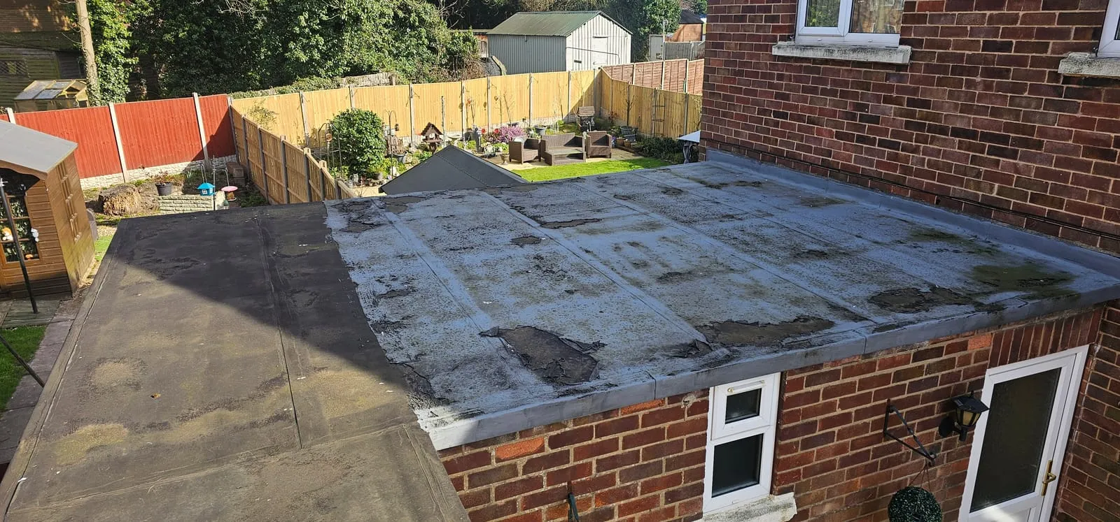 The old felt roof on the L-shaped extension in Lincoln: worn grey mineral felt, patched and stained, meeting a darker felt on the other wing