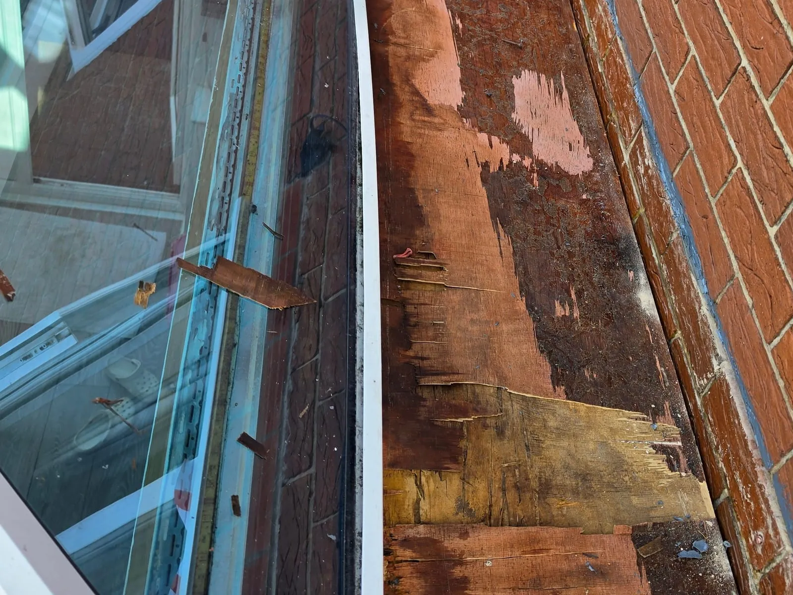 The strip between the roof lantern and the house wall in Flanderwell at 9.15 am, with the rubber roof off and the old boards underneath stained dark and breaking up