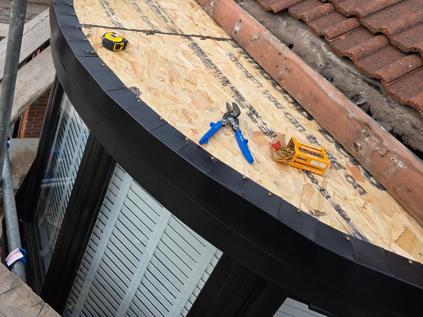 The curved dormer roof in Maltby at 2.27 pm, boarded in new OSB with a black edge trim round the curve, below the tiled main roof