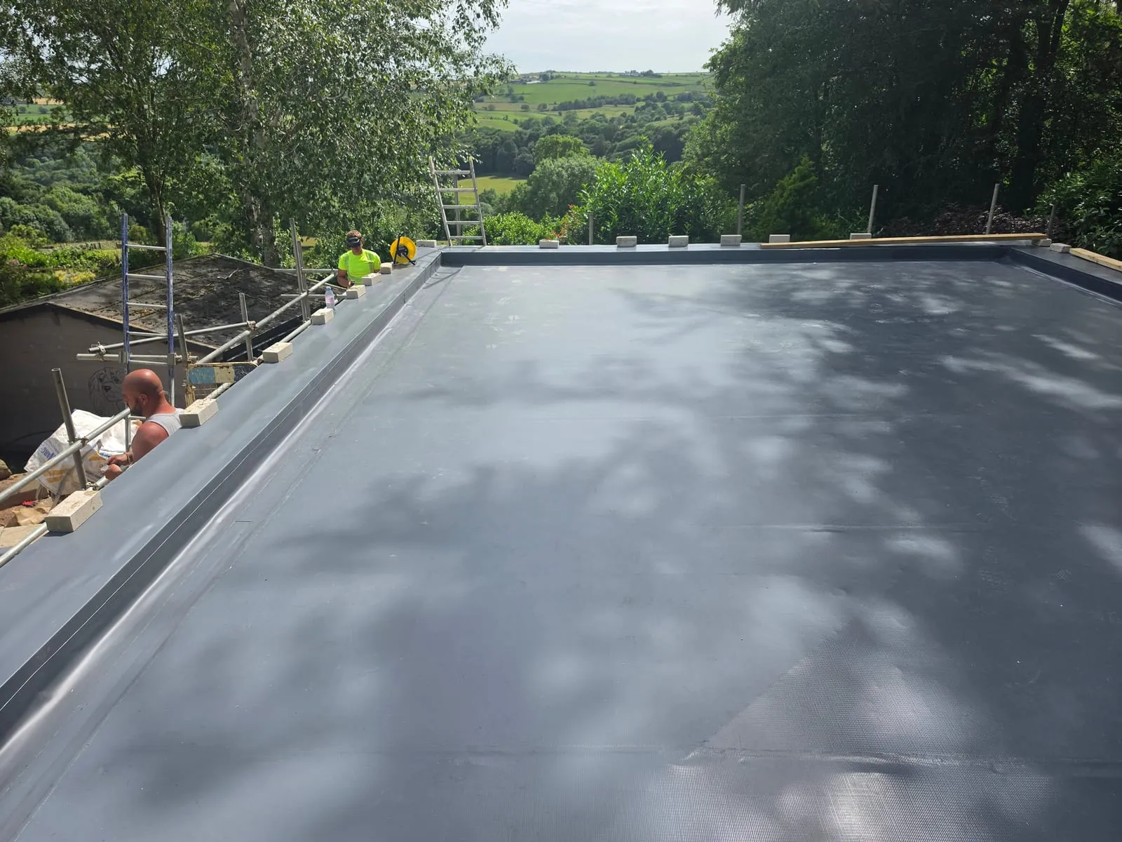 The same garage roof before the sedum layer — dark grey single ply membrane, heat-welded and ready for the green layer