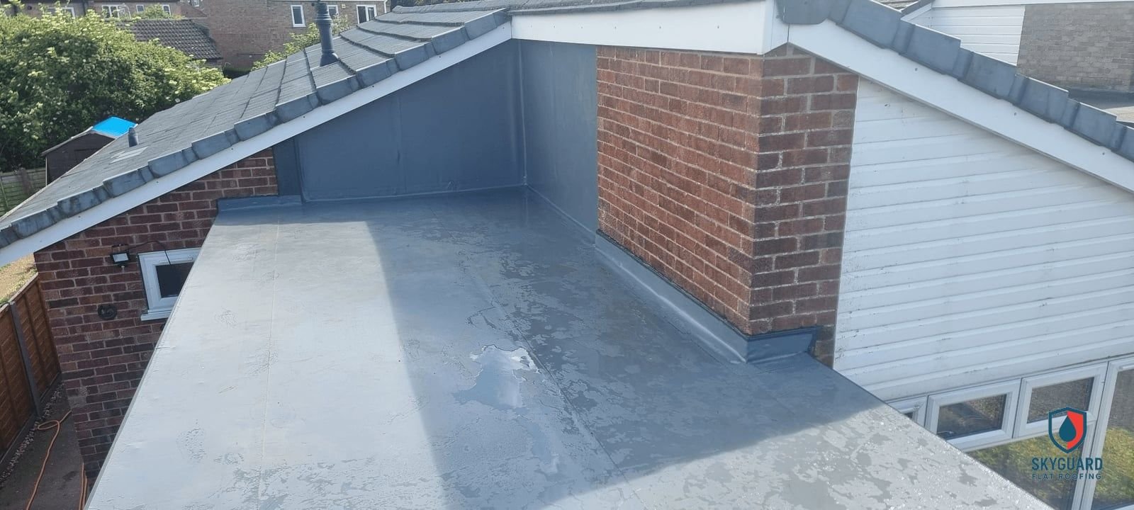 Grey single ply membrane flat roof between two pitched roofs, finished by Skyguard