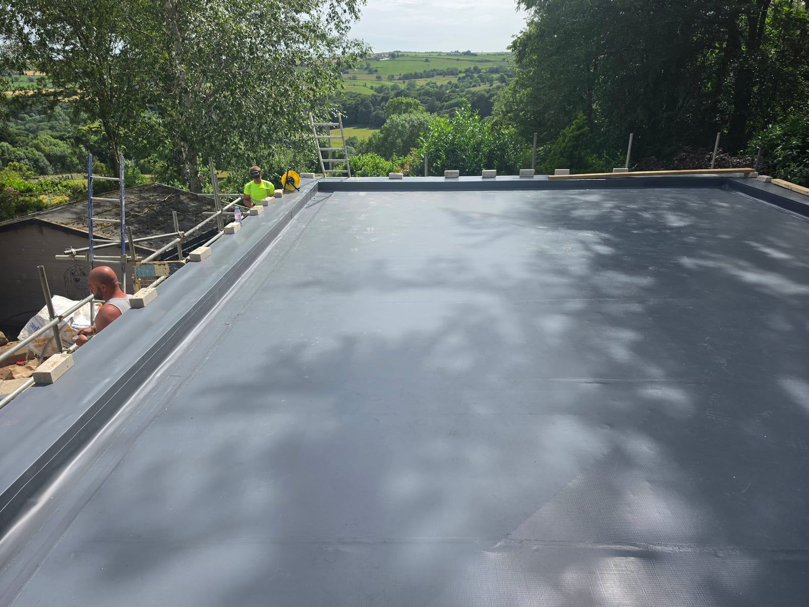 The same garage roof before the sedum layer — dark grey single ply membrane, heat-welded and ready for the green layer